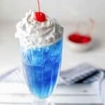 Copycat Ruby Tuesday Smurf Punch with whipped cream and a cherry on top.