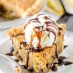 Classic Toll House pie topped with a scoop of vanilla ice cream and chocolate syrup drizzle.