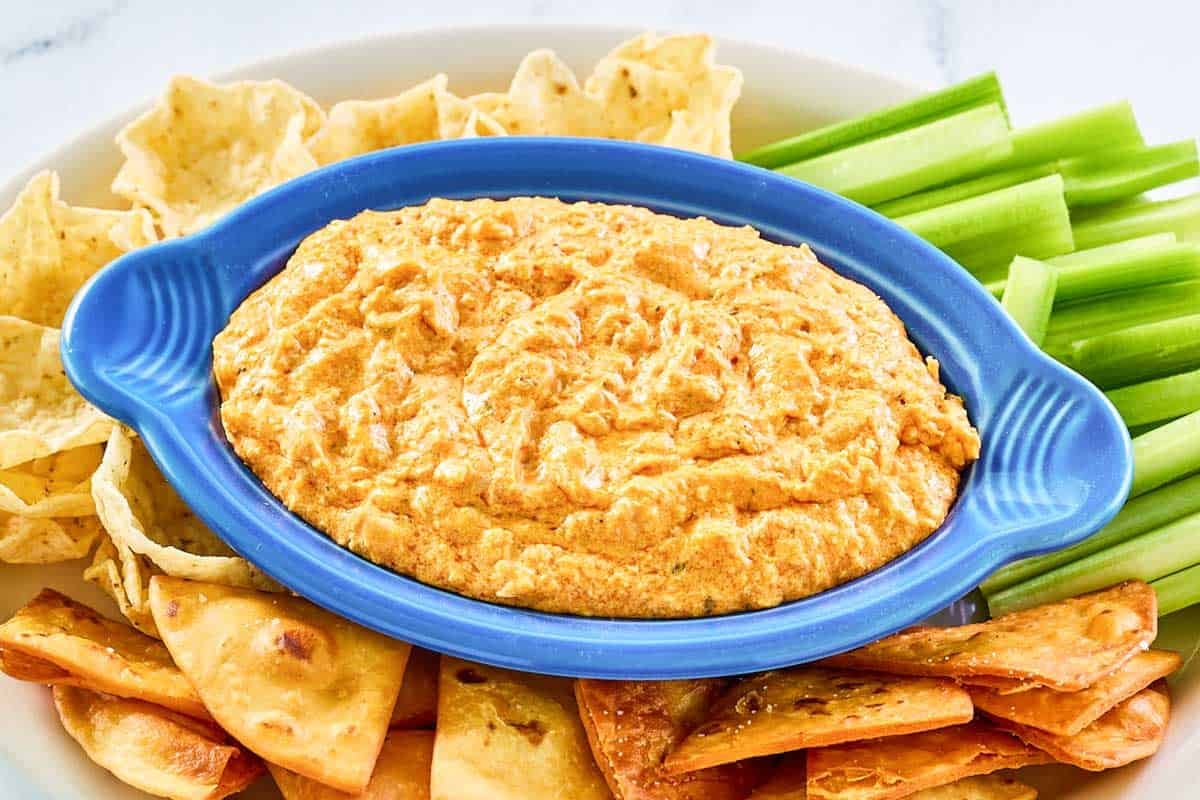 Cheesy chicken dip with buffalo sauce served with celery and tortilla chips.