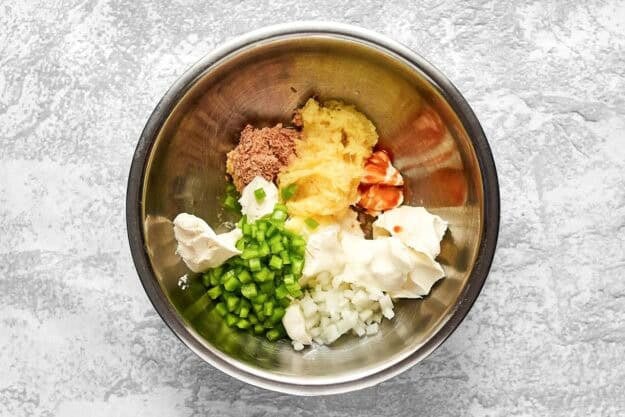 Deviled ham, cream cheese, bell pepper, onion, pineapple, and hot sauce in a mixing bowl.