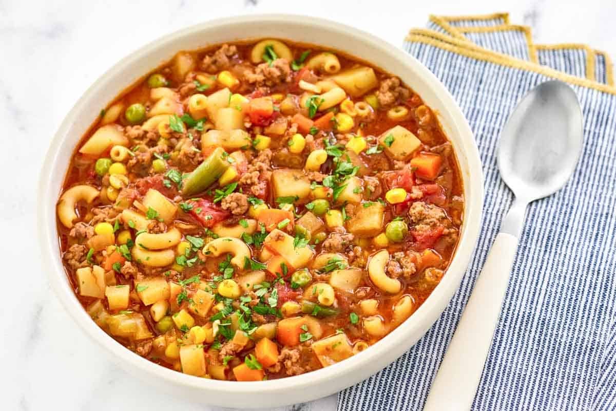 Ground beef, pasta, potato, vegetable, tomato soup in a bowl.