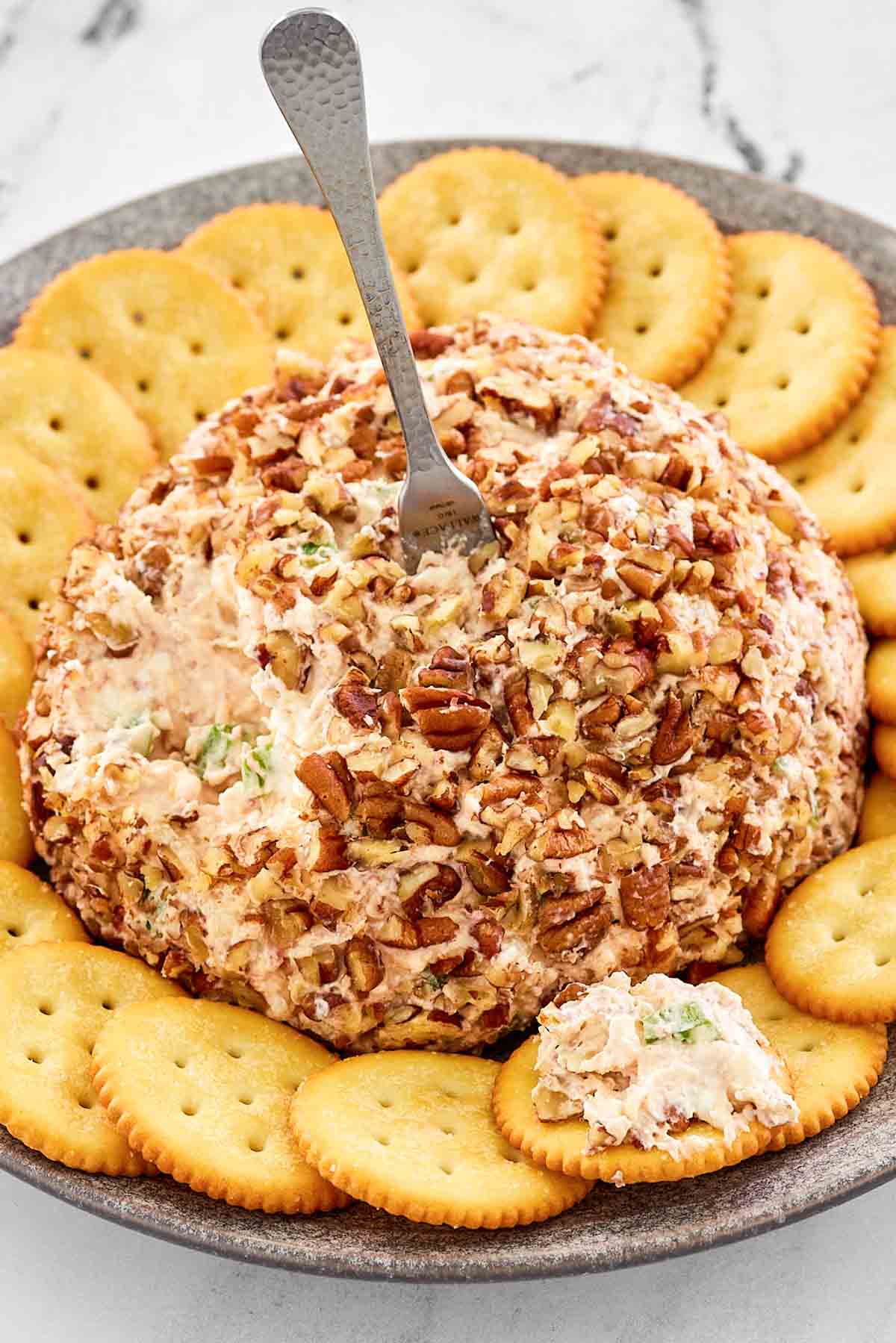 Pecan coated deviled ham cream cheese ball with crackers.