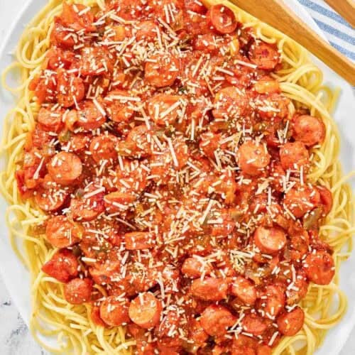 Spaghetti noodles topped with hot dog tomato sauce on a platter.