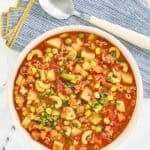 Tomato, ground beef, potato vegetable, and pasta soup in a large bowl.