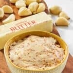 Copycat Benihana garlic butter in a bowl, a stick of butter, garlic cloves on a wooden platter.