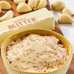 A bowl of copycat Benihana garlic butter, a stick of butter, and garlic cloves.