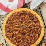 A whole copycat Dear Abby pecan pie on a wire rack and pecans beside it.
