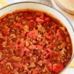 Homemade Indiana-style chili in a Dutch oven on a wooden surface.