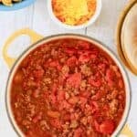 A pot of homemade Indiana-style chili, Fritos, and shredded cheese.