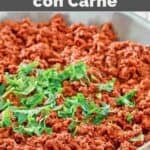 Copycat La Cocina chili Colorado con carne in a skillet on a wooden surface.