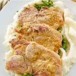 Mustard crusted baked pork chops, peas, and mashed potatoes on a platter.