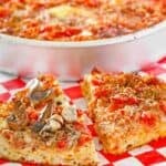 Copycat Pizzeria Uno deep dish pizza in the pan and slices on parchment paper.