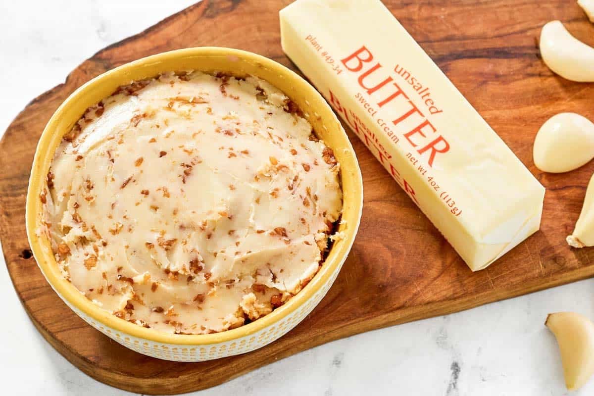 Soy, butter, and garlic mixture in a bowl, a stick of butter, and garlic cloves.